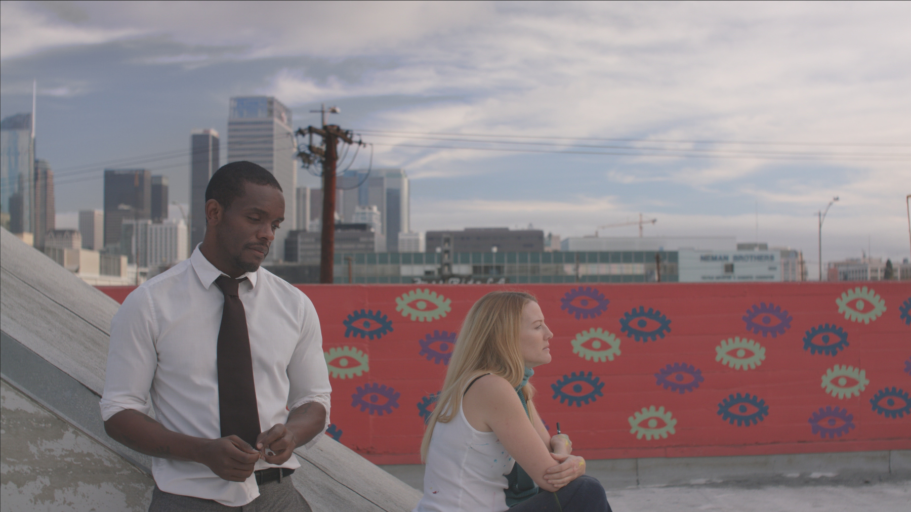 A woman sits on steps, looking away from a man standing next to her